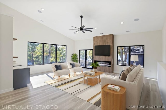 living room with high vaulted ceiling, recessed lighting, a fireplace, a ceiling fan, and light wood finished floors