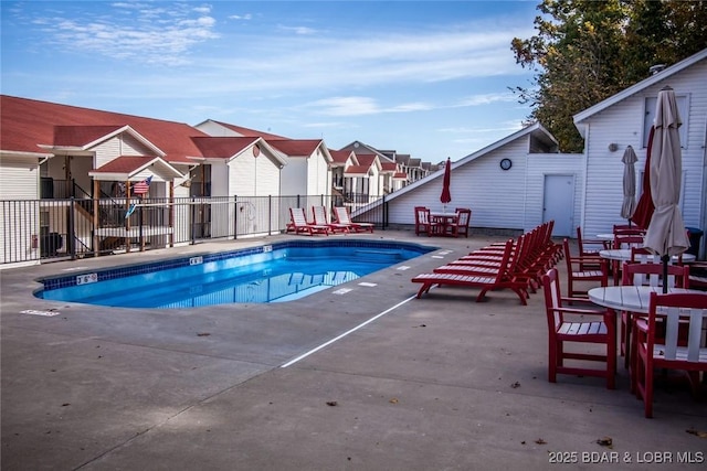 pool with a patio area, fence, and a residential view