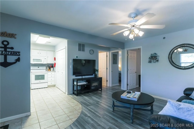 living room featuring light wood-style floors, baseboards, visible vents, and a ceiling fan