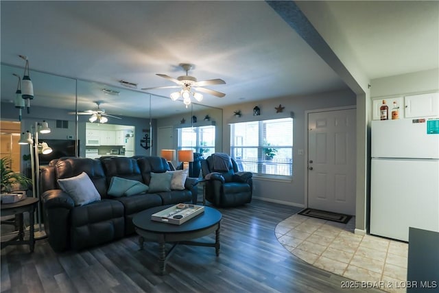 living area featuring baseboards, visible vents, ceiling fan, and wood finished floors