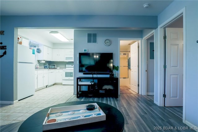 living area with light wood-style flooring, visible vents, and baseboards