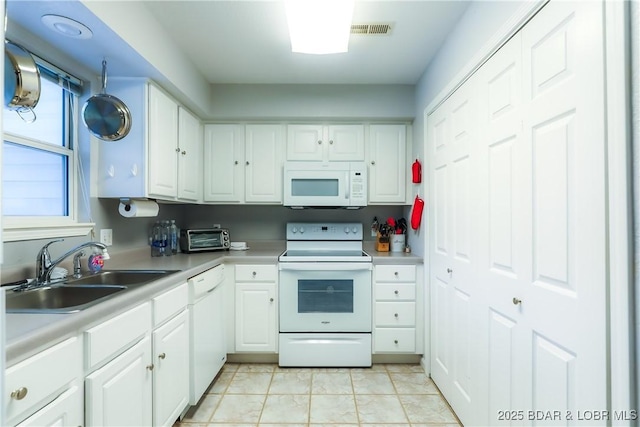 kitchen with light countertops, white appliances, a sink, and white cabinetry