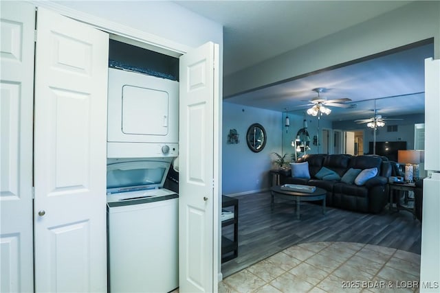 clothes washing area with laundry area, a ceiling fan, and stacked washer and clothes dryer