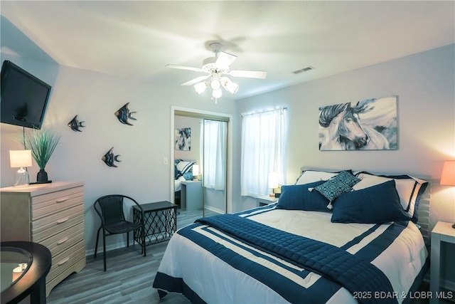 bedroom with a closet, visible vents, ceiling fan, wood finished floors, and baseboards