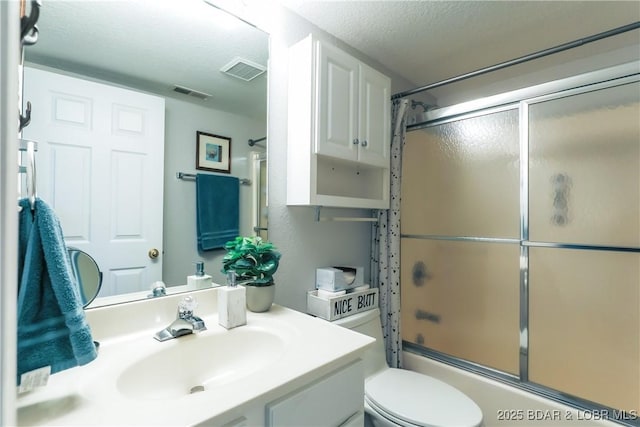 bathroom with toilet, visible vents, combined bath / shower with glass door, and a textured ceiling