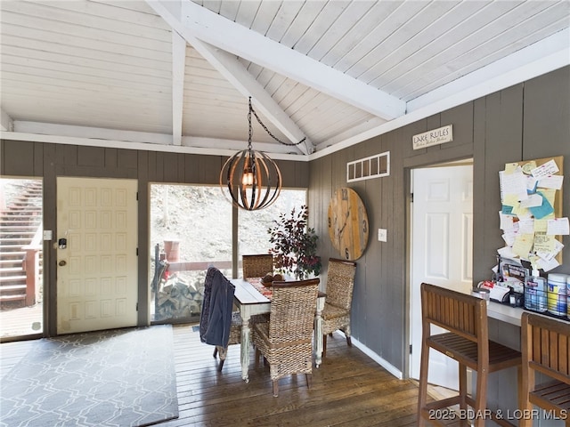 dining space featuring lofted ceiling with beams, visible vents, wood walls, and hardwood / wood-style flooring