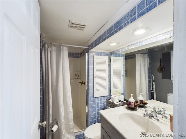 full bath featuring vanity, visible vents, a shower stall, tile walls, and toilet