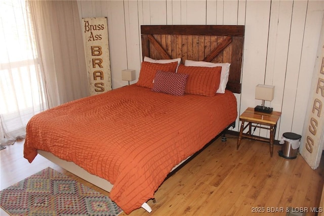 bedroom featuring wood walls and light wood-type flooring