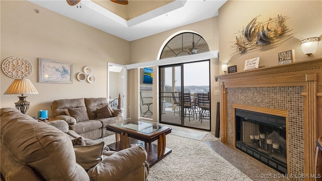 living room with a fireplace, a towering ceiling, and a ceiling fan