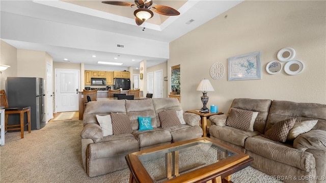 living area featuring visible vents, a ceiling fan, light colored carpet, a tray ceiling, and recessed lighting