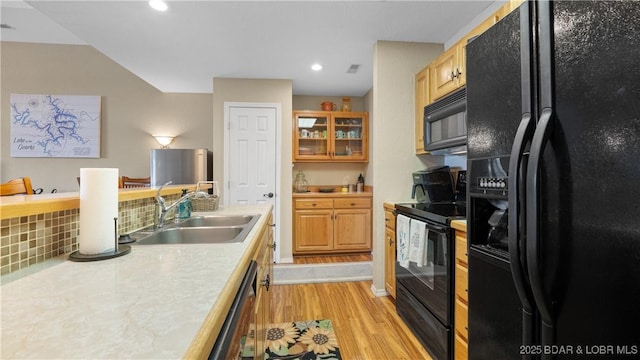 kitchen featuring light wood-style floors, light countertops, a sink, and black appliances