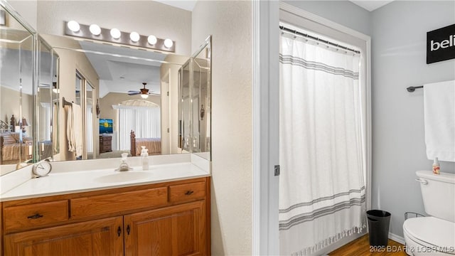 ensuite bathroom featuring curtained shower, toilet, a ceiling fan, connected bathroom, and vanity