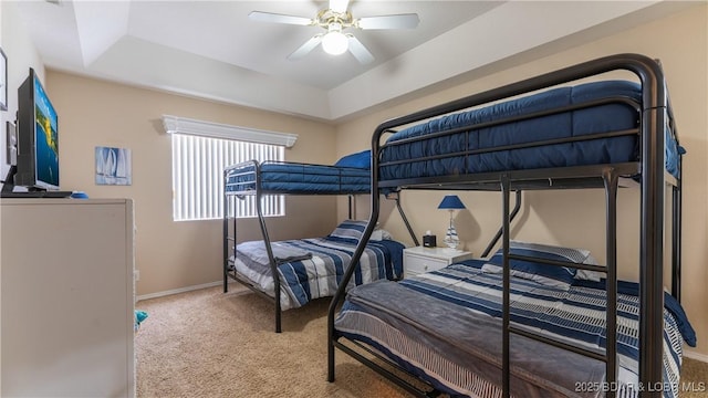 bedroom with carpet floors, a raised ceiling, baseboards, and a ceiling fan