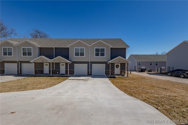 view of front of home featuring a garage, stone siding, and driveway