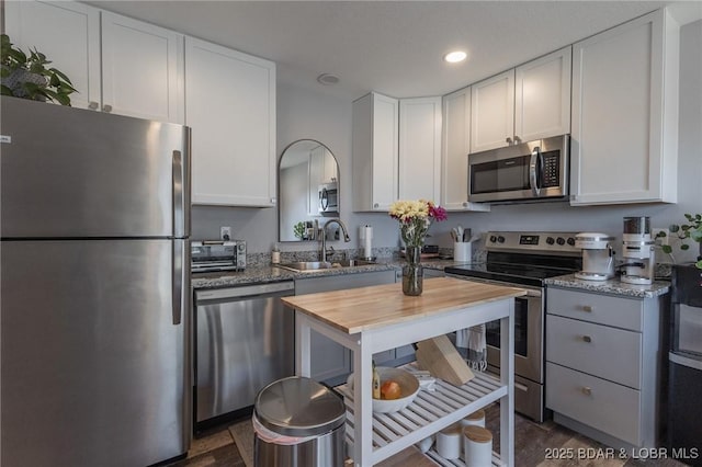 kitchen featuring white cabinetry, wood counters, appliances with stainless steel finishes, and a sink