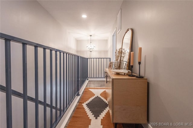 hallway featuring an inviting chandelier and wood finished floors