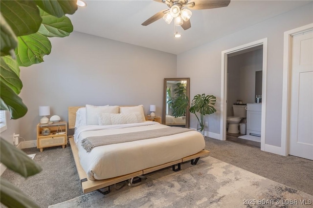 carpeted bedroom featuring ensuite bath, baseboards, and a ceiling fan