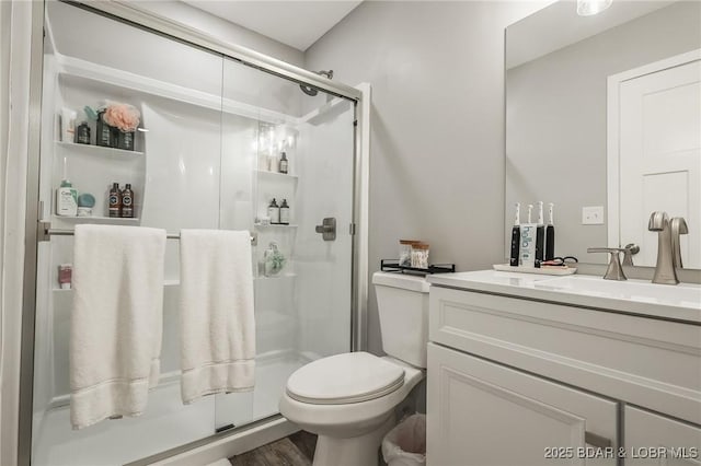 bathroom with wood finished floors, a stall shower, vanity, and toilet