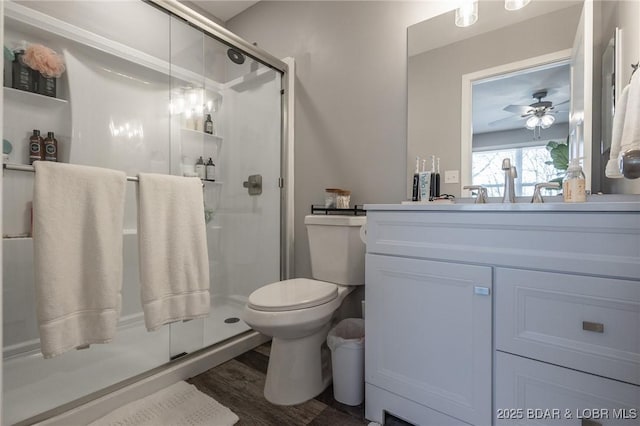 full bath with toilet, a ceiling fan, a stall shower, vanity, and wood finished floors