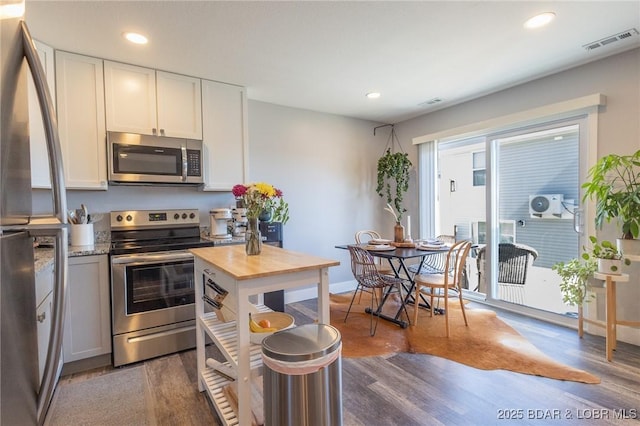 kitchen featuring appliances with stainless steel finishes, white cabinets, visible vents, and dark wood-type flooring