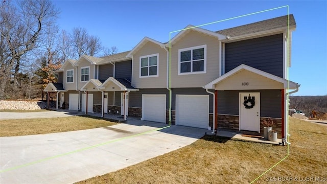 view of front of property featuring a garage, concrete driveway, stone siding, and a front lawn