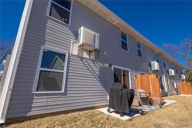 rear view of property featuring a wall unit AC and fence