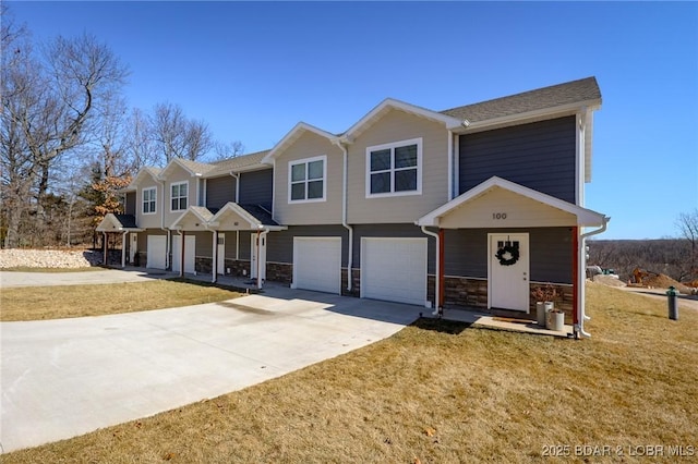 view of front of house with a front yard, stone siding, driveway, and an attached garage