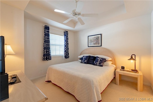 bedroom featuring ceiling fan, carpet, baseboards, and a raised ceiling