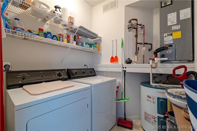 clothes washing area with laundry area, water heater, visible vents, and independent washer and dryer