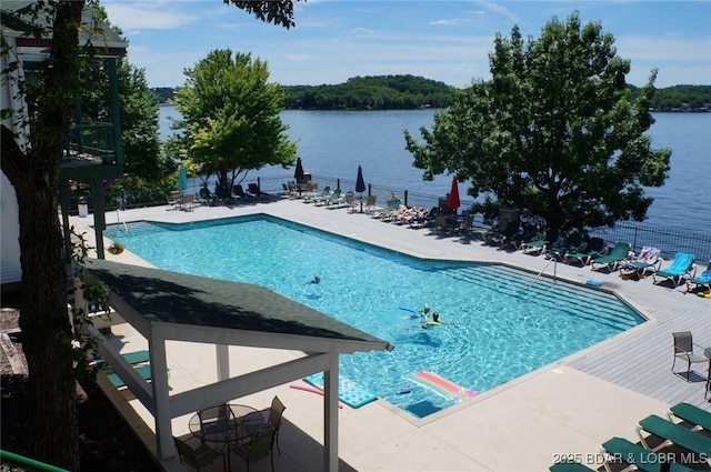 community pool with a patio, a water view, and fence