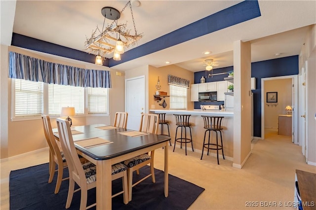 dining room featuring light carpet, baseboards, and a tray ceiling