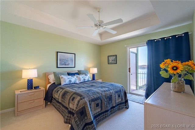 bedroom featuring access to exterior, a raised ceiling, light colored carpet, and baseboards