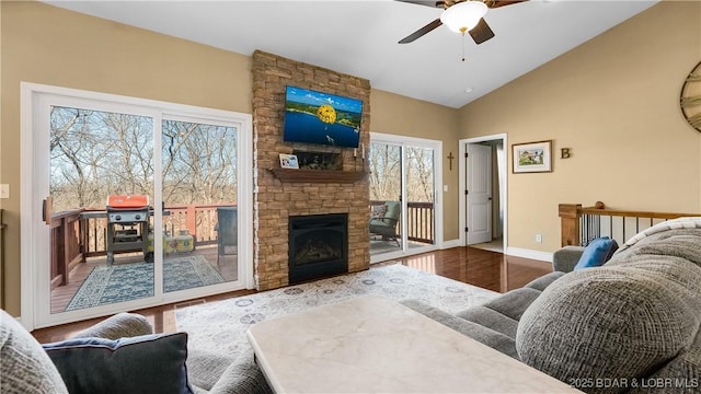 living area with a fireplace, ceiling fan, vaulted ceiling, wood finished floors, and baseboards