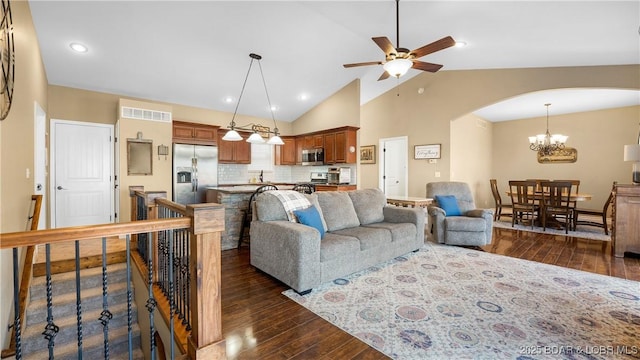 living area featuring arched walkways, high vaulted ceiling, dark wood-type flooring, and ceiling fan with notable chandelier