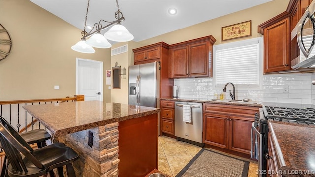 kitchen featuring stainless steel appliances, hanging light fixtures, visible vents, and decorative backsplash