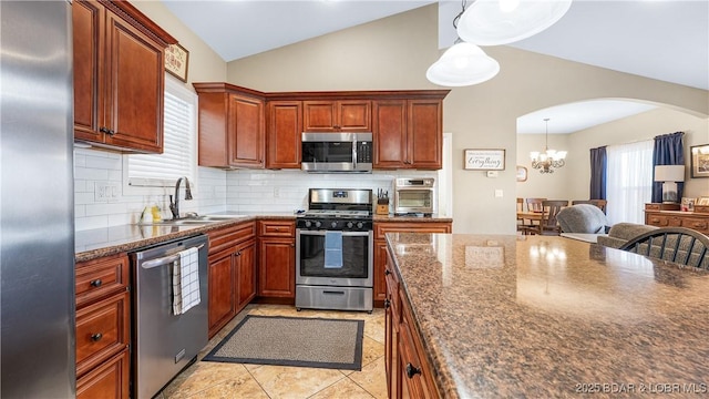 kitchen featuring arched walkways, a sink, vaulted ceiling, stainless steel appliances, and backsplash