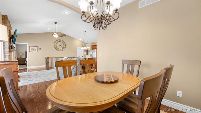 dining space featuring ceiling fan with notable chandelier, wood finished floors, visible vents, baseboards, and vaulted ceiling