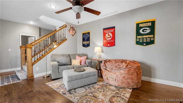 living room featuring visible vents, baseboards, wood finished floors, a ceiling fan, and stairs