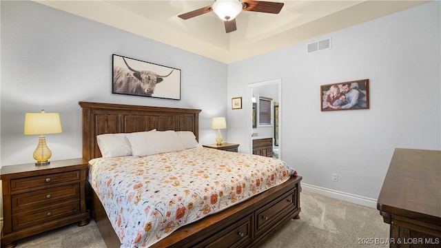 carpeted bedroom with baseboards, visible vents, a raised ceiling, a ceiling fan, and ensuite bathroom