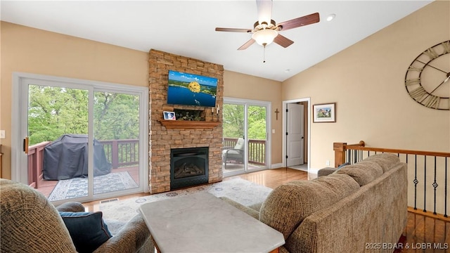 living room featuring ceiling fan, baseboards, vaulted ceiling, a fireplace, and wood finished floors