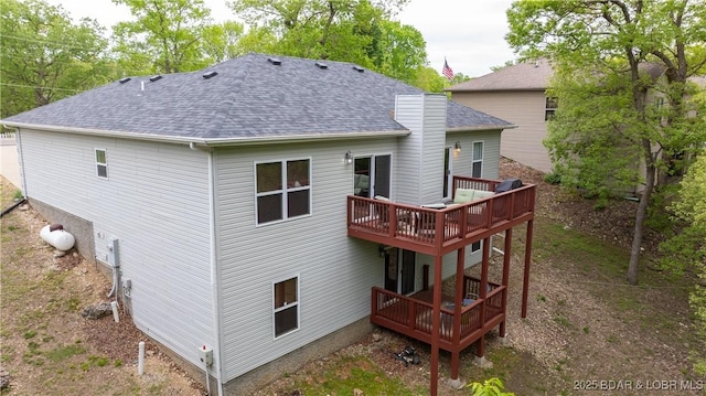 rear view of house with a deck and roof with shingles