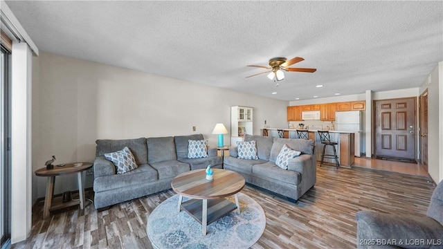 living area featuring a textured ceiling, wood finished floors, a ceiling fan, and recessed lighting