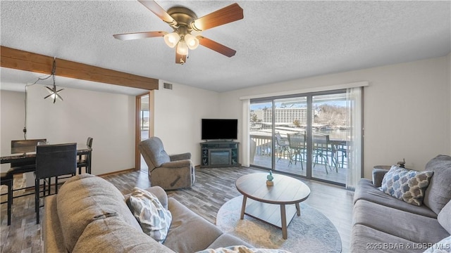 living area with visible vents, ceiling fan, a textured ceiling, and wood finished floors