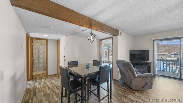 dining area featuring baseboards, a textured ceiling, visible vents, and wood finished floors