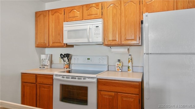 kitchen featuring white appliances, light countertops, and brown cabinetry