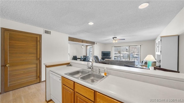 kitchen with light countertops, visible vents, open floor plan, white dishwasher, and a sink