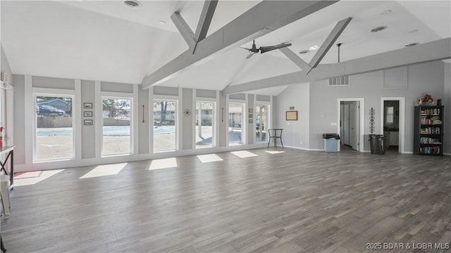 unfurnished living room featuring ceiling fan, beamed ceiling, wood finished floors, and a wealth of natural light