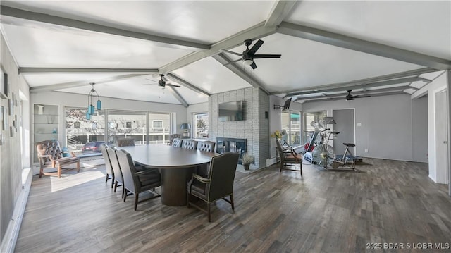 dining space with vaulted ceiling with beams, a fireplace, dark wood finished floors, and a ceiling fan