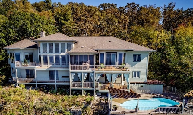 rear view of property with a fenced in pool, a sunroom, a chimney, stairs, and a patio area