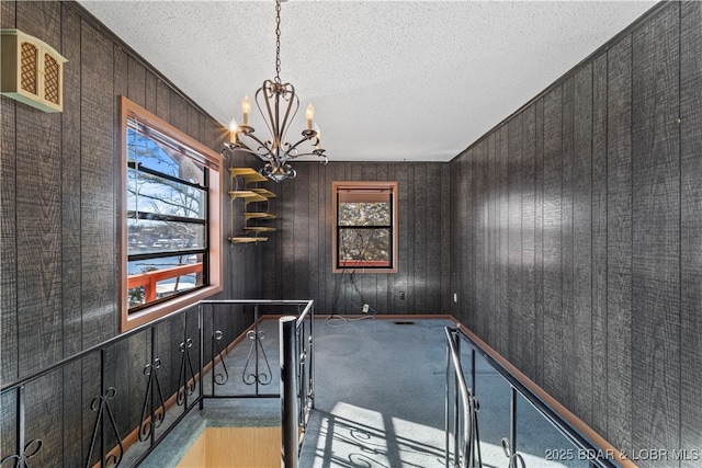 interior space featuring an inviting chandelier, a textured ceiling, and carpet flooring